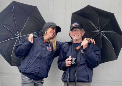 Veteran and his guardian standing under umbrellas during an Honor Flight trip.