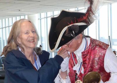 "A Paul Revere reenactor, dressed in period attire, gently kisses the hand of a woman veteran at the Honor Flight homecoming ceremony, symbolizing deep respect and admiration for her service.