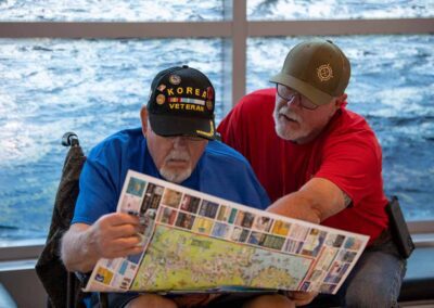 Guardian assisting a veteran in reading a pamphlet during their Honor Flight trip.